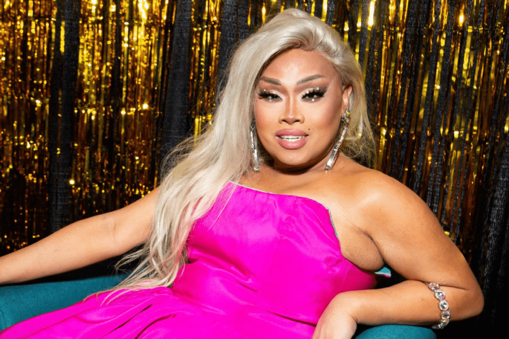 Jiggly Caliente smiling during a Drag Race Philippines judging panel, wearing a colorful outfit